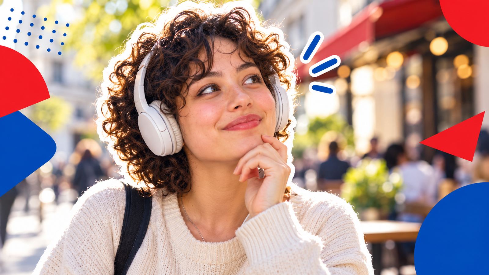A woman with earphones smiling as she follows a conversation, her lips closed, about to speak