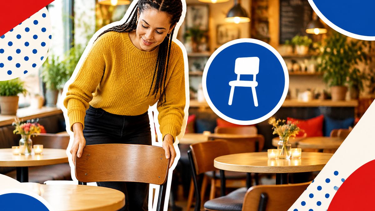 An organiser arranging chairs around small tables in a cosy, warmly lit café before participants arrive