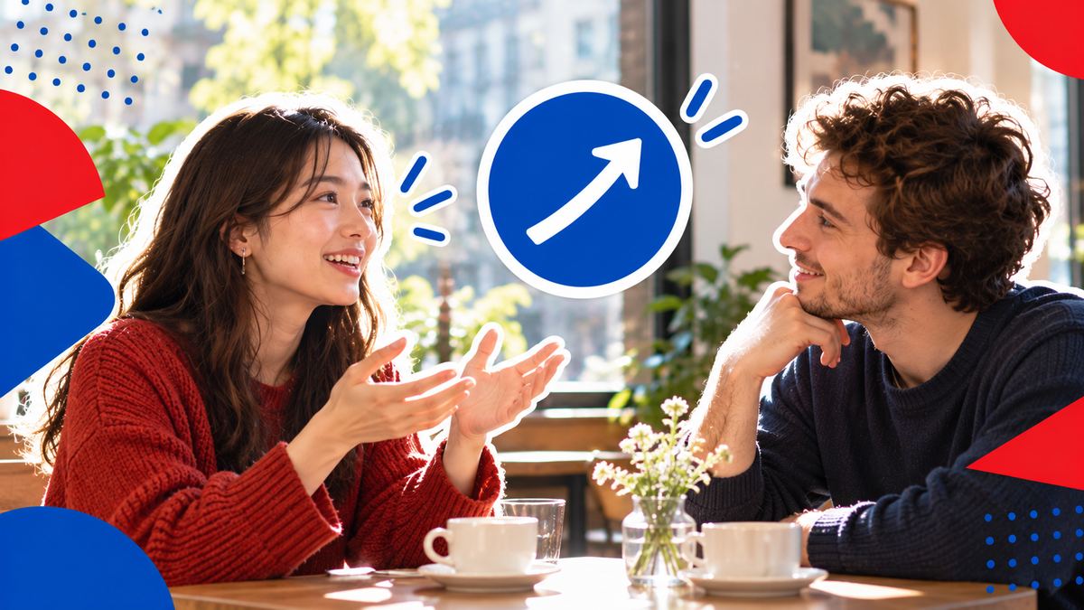 Two people at a small café table, one speaking with a confident smile while the other nods encouragingly